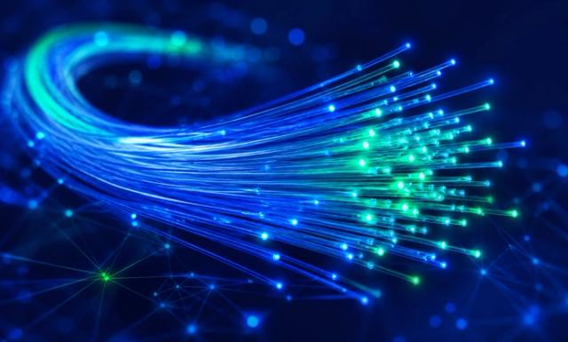 Conteúdo fala sobre o que é fibra óptica. Imagem com preto ao fundo e uma imagem de filamentos de fibra óptica em tons azuis brilhosos.